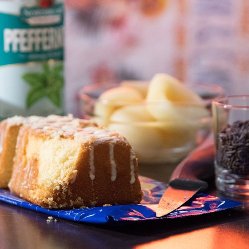 Das Bild zeigt ein Stück Kuchen, Birnenscheiben und eine Flasche Pfeffi im Anschnitt