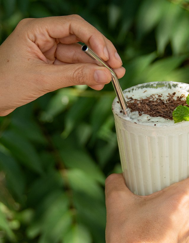 Das Bild zeigt eine Hand, die einen Milchshake mit einem Minzzweig hält