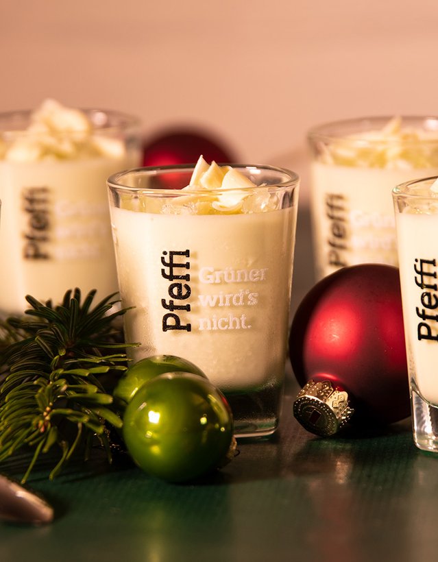 Man sieht ein weißes Mousse in Pfeffi Pinnchen nebst Weihnachtsdekoration
