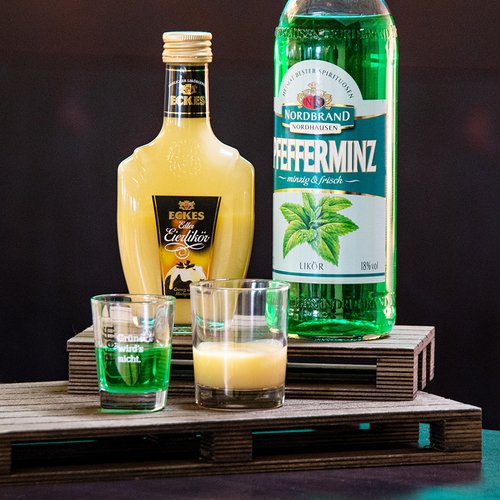 Das Bild zeigt eine Flasche Eckes Eierlikör und eine Flasche Pfeffi auf einer Palette