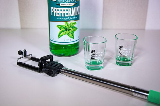 Man sieht einen Selfiestick, zwei Pfeffi Pinnchen und eine Pfeffi Flasche