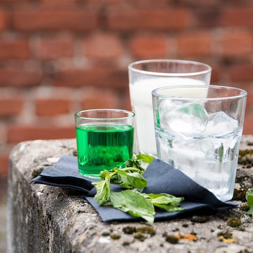 Das Bild zeigt ein Glas mit Milch, eins mit Pfeffi und eins mit Eiswürfeln auf einer Mauer