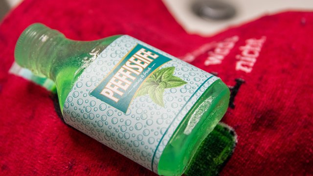 Das Bild zeigt eine grüne Seife in Pfeffi Flaschenform mit einer Banderole, auf der "Pfeffiseife" steht.