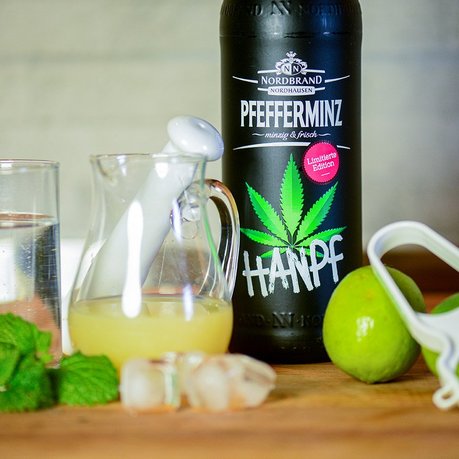 Pfeffi Rezept Hanpf Tonic Man sieht eine Flasche Pfeffi Hanpf, Zitronensaft, Eiswürfel, eine Limette, Minze und Tonicwater