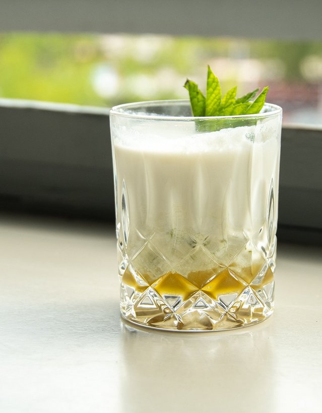 Pfeffi Rezept Coco Mintjito Das Bild zeigt einen cremigen Cocktail auf einer Fensterbank.