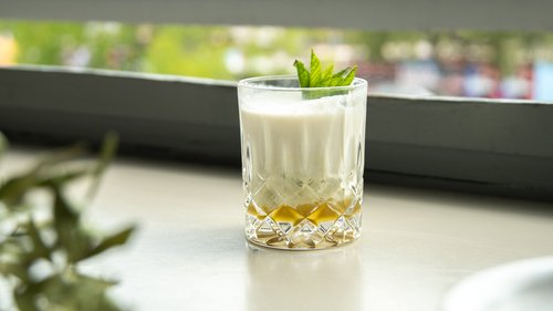 Pfeffi Rezept Coco Mintjito Das Bild zeigt einen cremigen Cocktail auf einer Fensterbank.