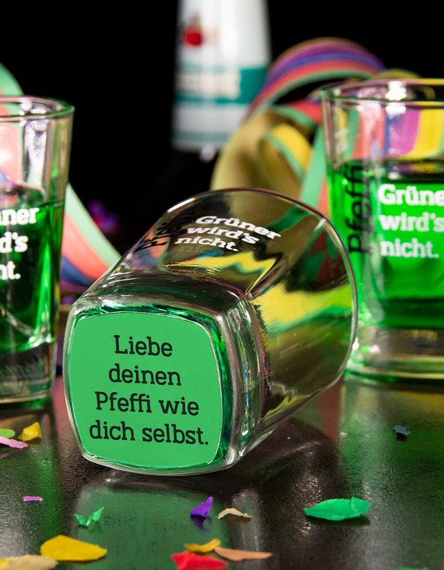 DIY: Glücksshot Das Bild zeigt mehrere gefüllte Pfeffi Pinnchen. Ein leeres Pinnchen im Vordergrund ist so gekippt, dass man einen Spruch auf dem Boden sieht. Darauf steht " Liebe deinen Pfeffi, wie dich selbst!"
