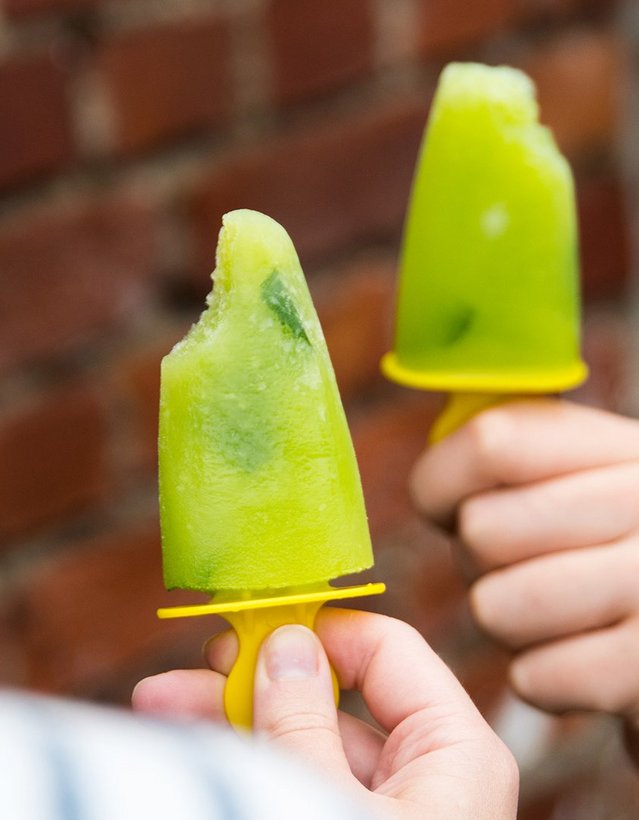 Pfeffi Rezept Eis am Stil Das Bild zeigt eine Hand, die ein grün-gelbes Eis am Stil vor sich hält
