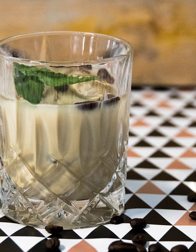 Pfeffi Rezept Pfefficino Das Bild zeigt einen kaffeebraunen Cocktail auf einer gemusterten Tischdecke