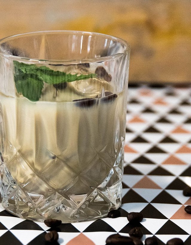 Pfeffi Rezept Pfefficino Das Bild zeigt einen kaffeebraunen Cocktail auf einer gemusterten Tischdecke