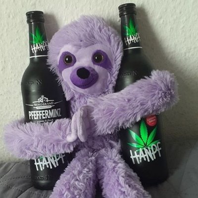 Hanpf Fanbild 7 Das Bild zeigt ein lilafarbenes Affenkuscheltier, das in jedem Arm eine Hanpf Flasche hält