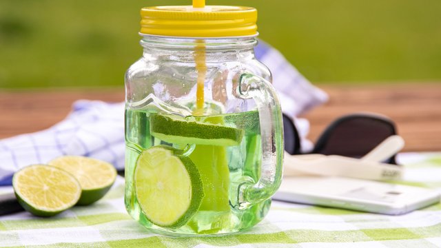 Das Bild zeigt einen Pfeffi Cocktail mit Strohhalm und Limettenscheiben 