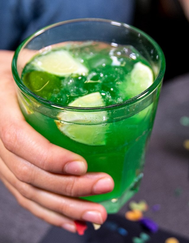 Pfeffi Rezept Raketenstart Das Bild zeigt eine Hand, die einen Pfeffi Cocktail anhebt, in dem Zitronen und Eis schwimmen