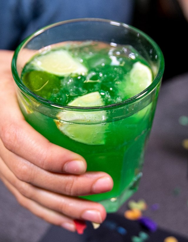 Pfeffi Rezept Raketenstart Das Bild zeigt eine Hand, die einen Pfeffi Cocktail anhebt, in dem Zitronen und Eis schwimmen