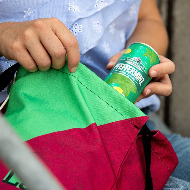 Pfeffi Merchandise Das Bild zeigt eine Pfeffi Dose, die in den Pfeffi Turnbeutel gesteckt wird