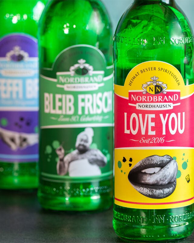 Pfeffi Etikettengenerator Das Bild zeigt mehrere Pfeffi Flaschen mit alternativen Etiketten in einer Reihe. Auf dem Vordersten steht, dort, wo sonst Pfefferminz steht: "love you". Statt der Minze ist ein Mund aufgedruckt.