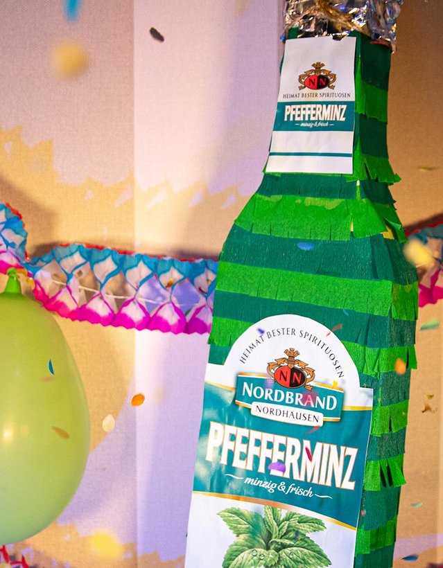 Das Bild zeigt eine Pinata in Pfeffi Flaschenform in eine Partykulisse