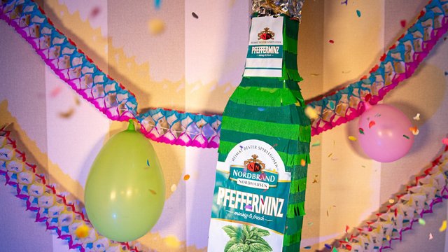 Das Bild zeigt eine Pinata in Pfeffi Flaschenform in eine Partykulisse