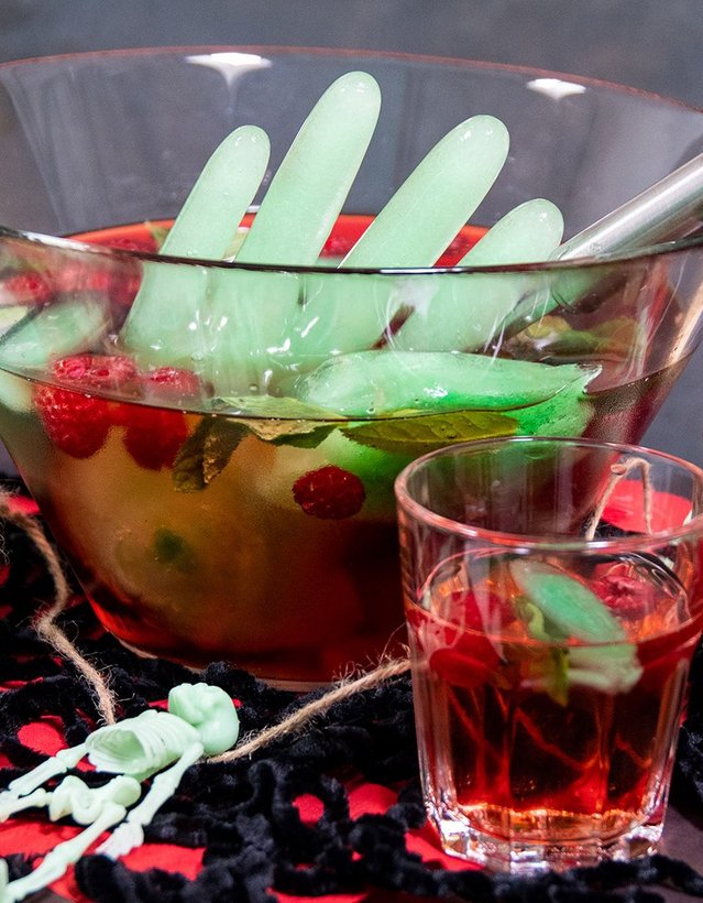 DIY: Eiskaltes Händchen Das Bild zeigt eine Bowle, die von Halloweendeko umgeben ist. Aus der Bowle ragt eine Hand aus grünem Eis