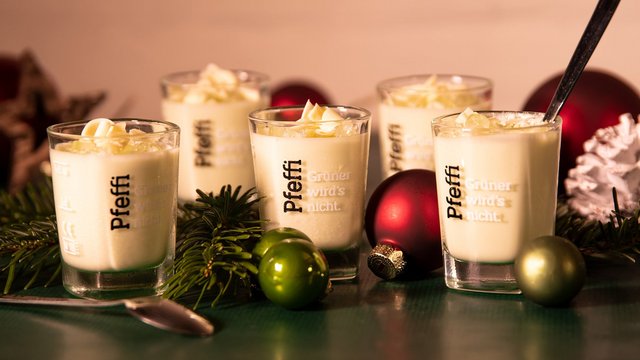 Man sieht ein weißes Mousse in Pfeffi Pinnchen nebst Weihnachtsdekoration