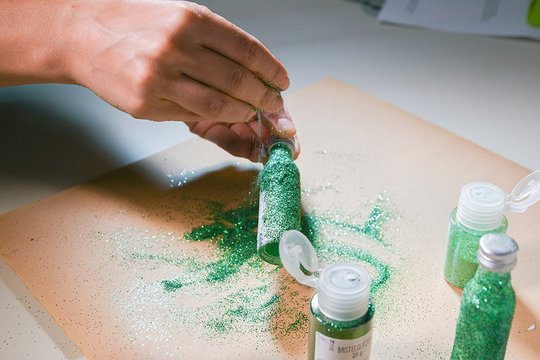 Das Bild zeigt, wie die Pfeffi Fläschchen mit grünen Glitzer bedeckt werden